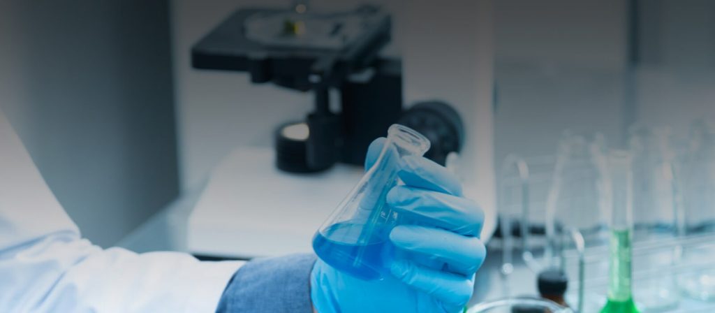 A scientist holding a test tube containing blue liquid.