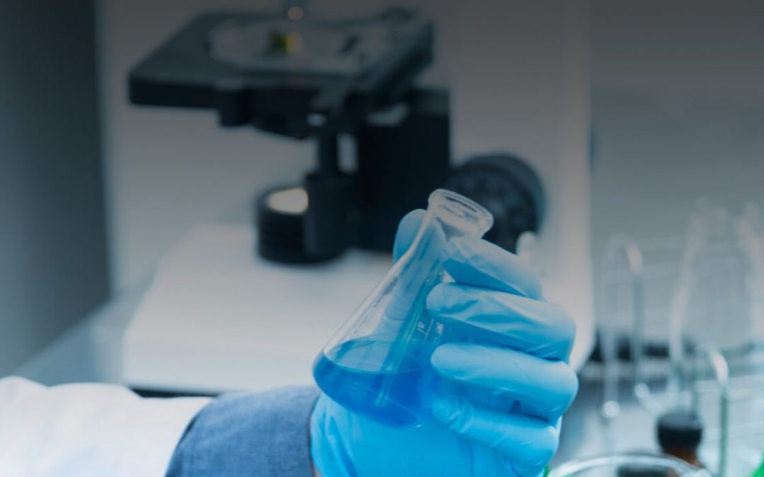 A scientist holding a test tube containing blue liquid.